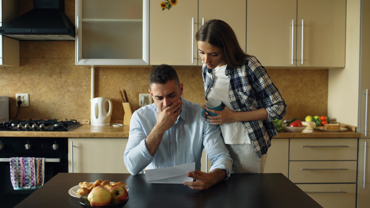 Couple looking stressed over bills and documents at kitchen table